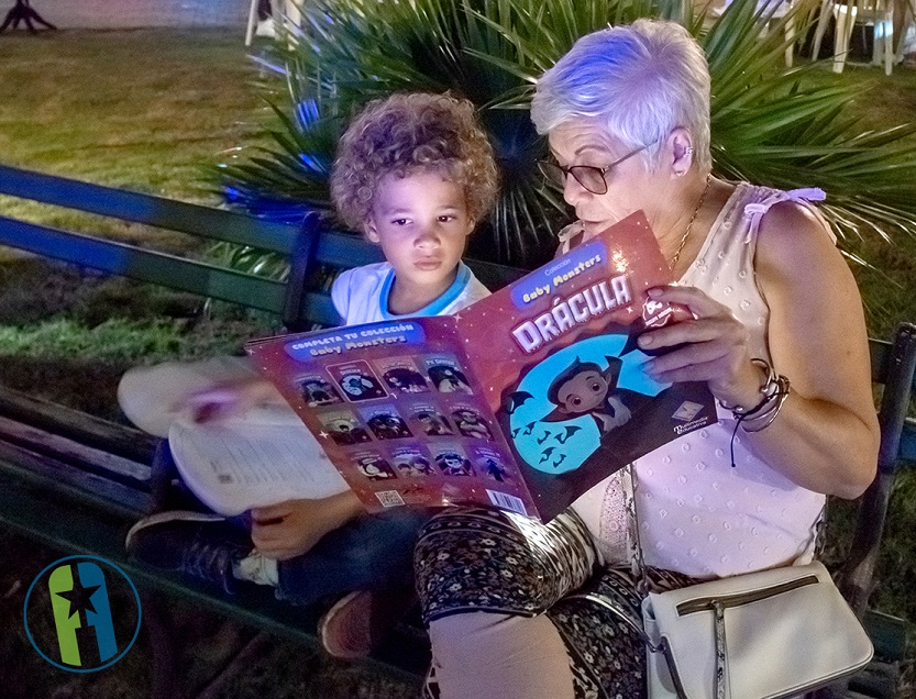 La abuela leyendo cuentos al nieto en un parque.