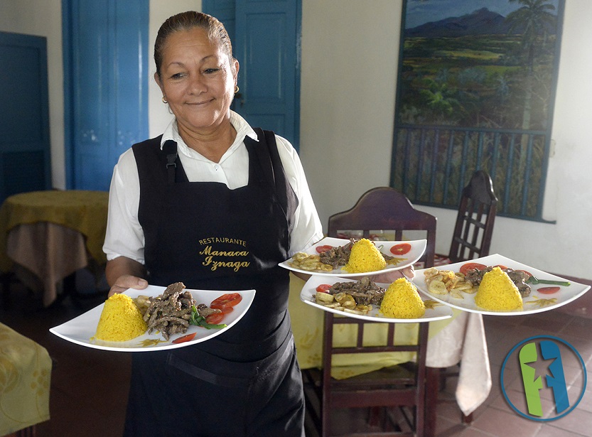 Una camarera lleva los platos servidos a la mesa un restaurante de La Habana. 